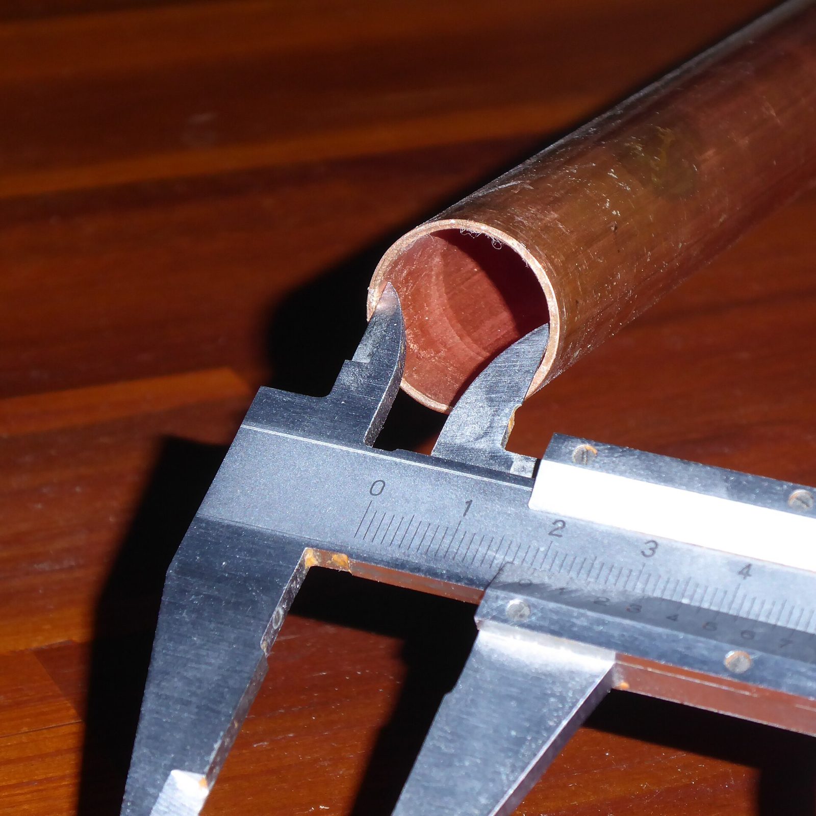 Un calibrador vernier midiendo el diámetro interior de un tubo de cobre.