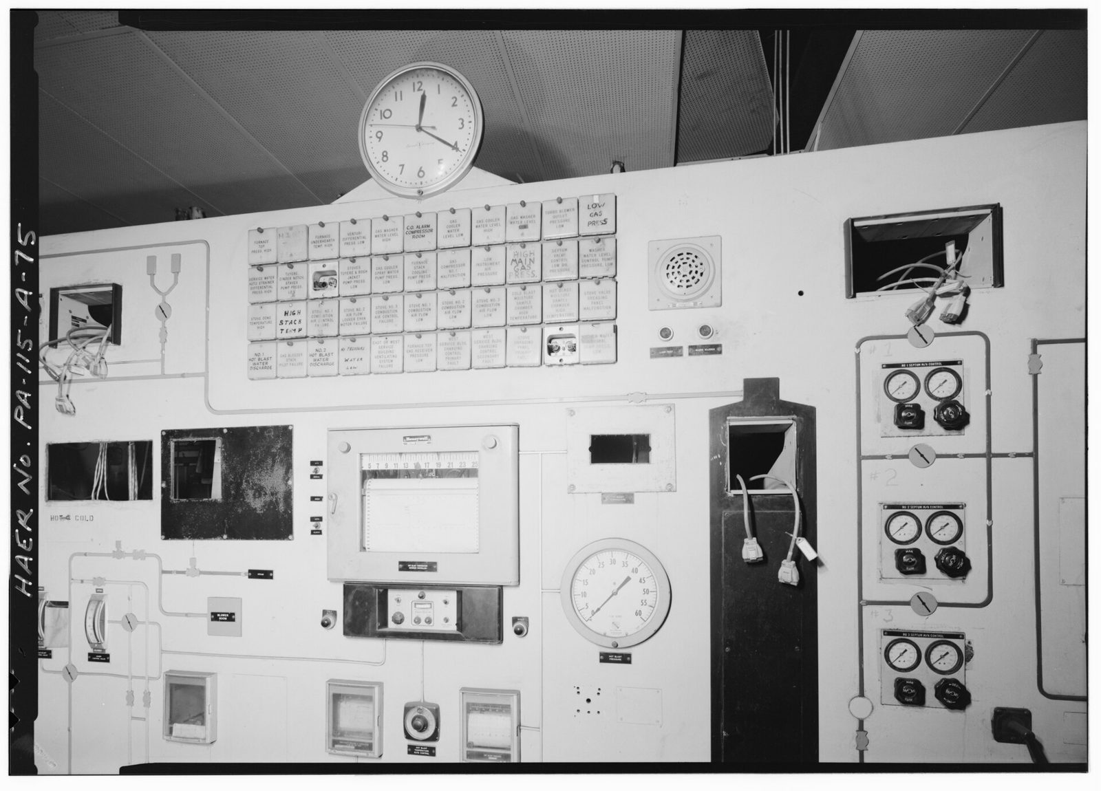 Un tablero de control industrial grande con manómetros, interruptores y luces indicadoras.